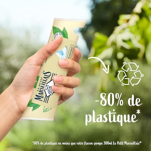 Main tenant une bouteille de plastique recyclable.