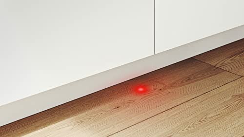 Point rouge lumineux sur un sol en bois près d'un meuble blanc.