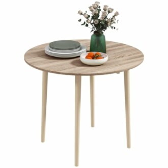 Table ronde en bois avec vaisselle et vase de fleurs.