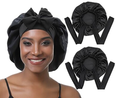Femme portant un bonnet en satin noir avec un nœud, deux bonnets supplémentaires à côté.