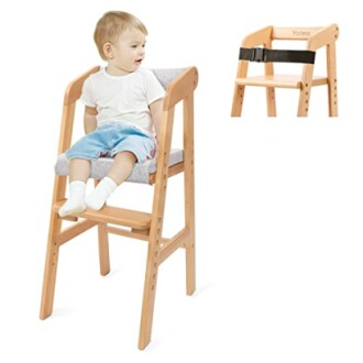 Enfant assis sur une chaise haute en bois avec coussin gris.