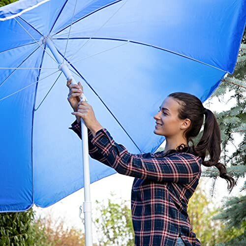 Femme ajustant un grand parapluie bleu.