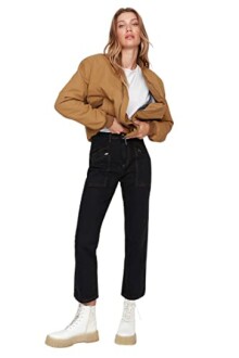 Femme en veste marron et jeans noirs, portant des bottes blanches.