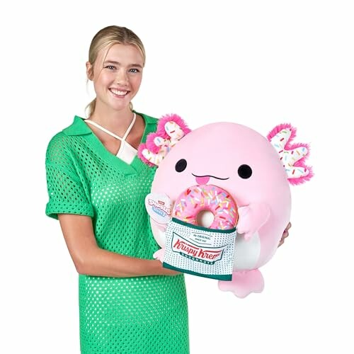 Femme tenant une peluche axolotl rose avec un beignet.