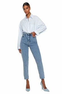 Femme portant une chemise blanche et un jean bleu.