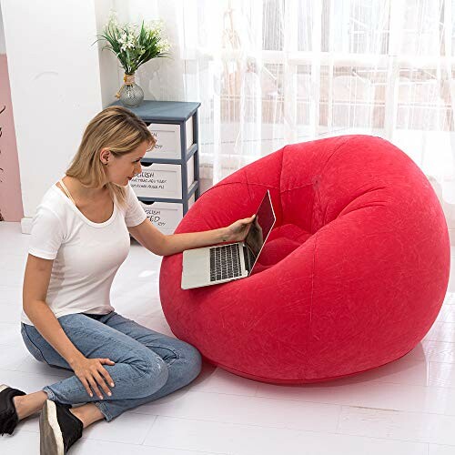 Femme assise près d'un pouf rouge avec un ordinateur portable.