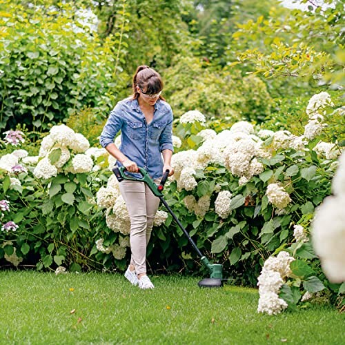 Femme utilisant une tondeuse à gazon dans un jardin fleuri.