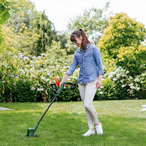 Femme utilisant une tondeuse à gazon dans le jardin.