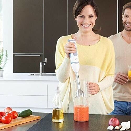 Femme utilisant un mixeur plongeant dans la cuisine.