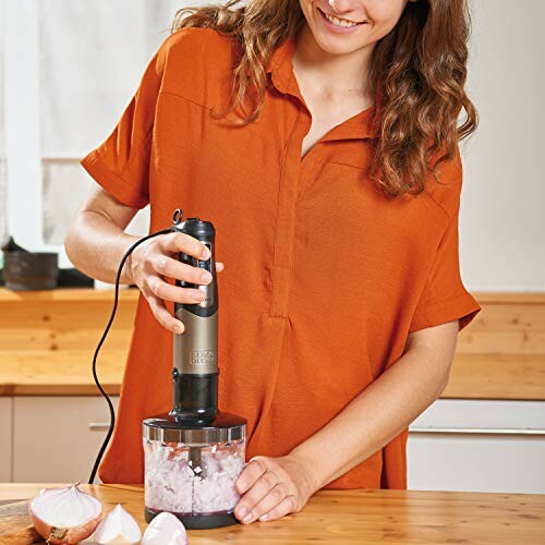 Femme utilisant un mixeur plongeant dans la cuisine.