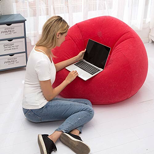 Femme utilisant un ordinateur portable sur un pouf rouge