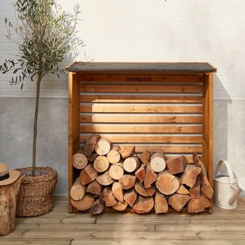 Rangement de bûches en bois à côté d'un arbre et d'un panier.