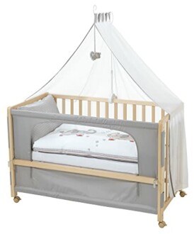 Lit bébé en bois avec baldaquin et matelas.