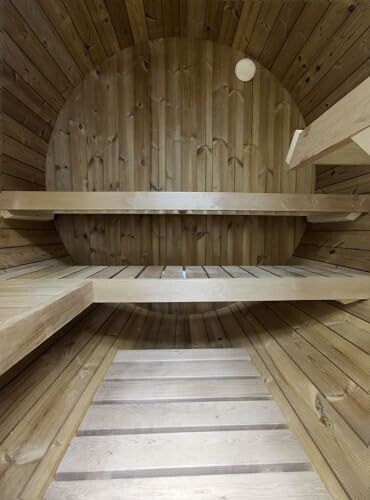 Intérieur d'un sauna en bois en forme de tonneau avec des bancs.
